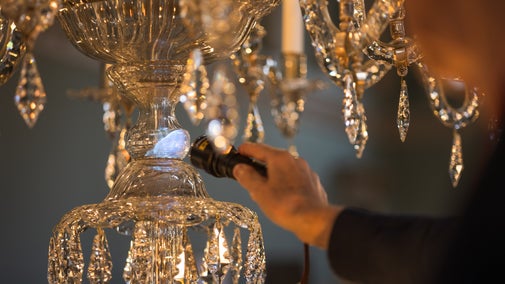 A close-up of someone inspecting one of the chandeliers with a torch.